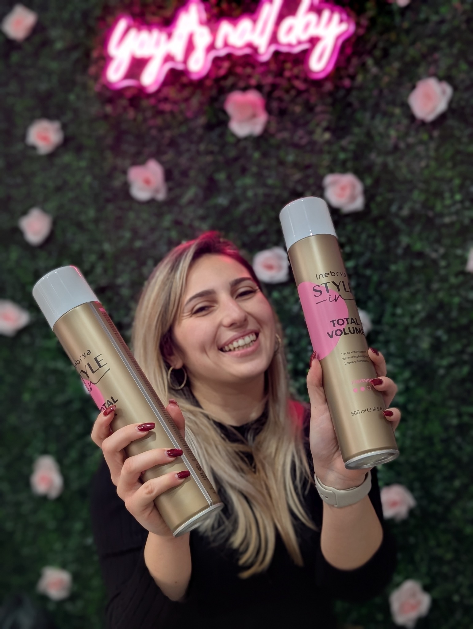 Desailee with Inebrya styling spray in front of the floral salon wall