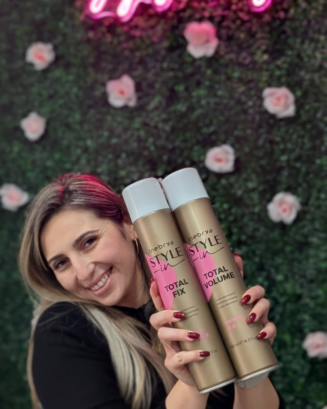 Desailee smiling while presenting two Inebrya styling sprays