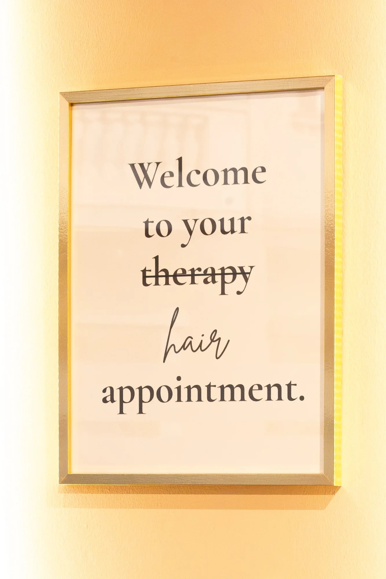 Gold-framed welcome sign at Hair by Desailee