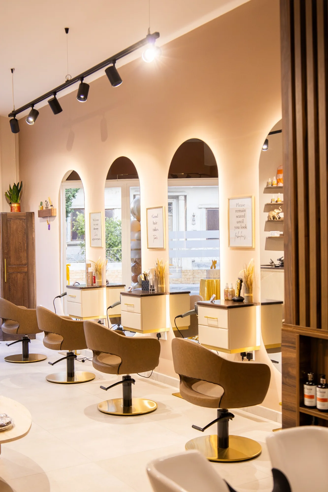 Finished salon styling stations with illuminated arched mirrors and brown chairs