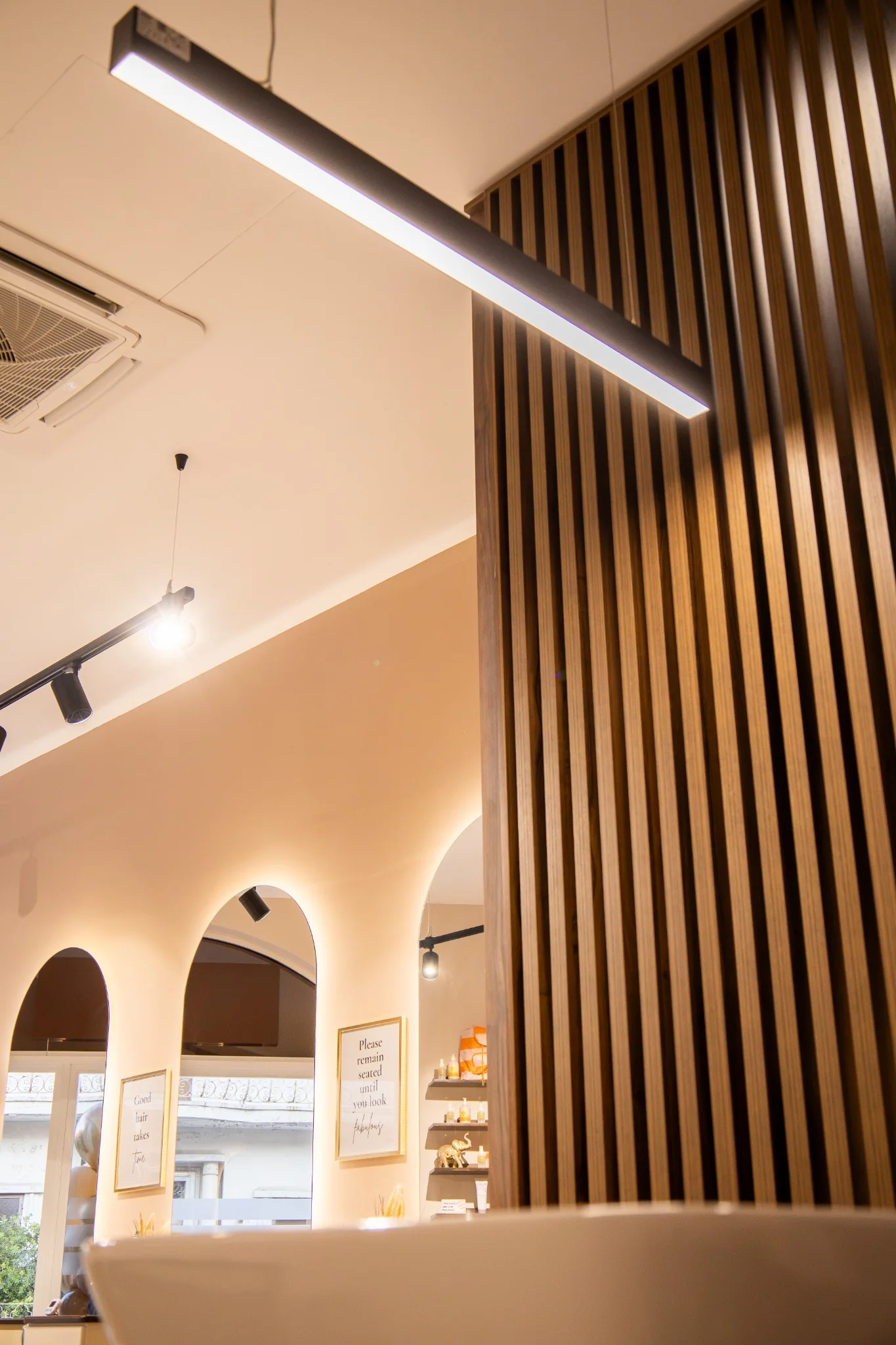 Custom wooden slat partition with warm salon lighting